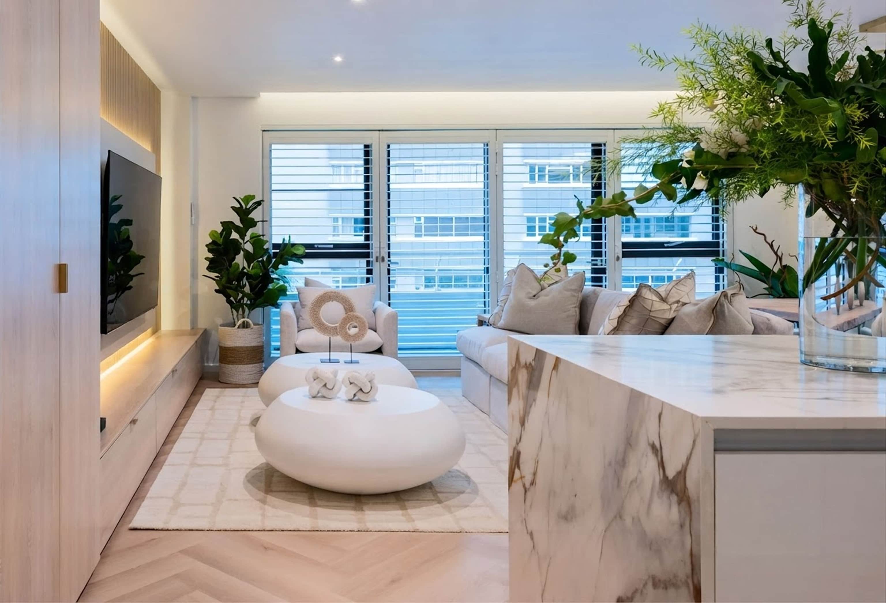 Living room with a herringbone oak floor, white oval coffee tables and shuttered windows