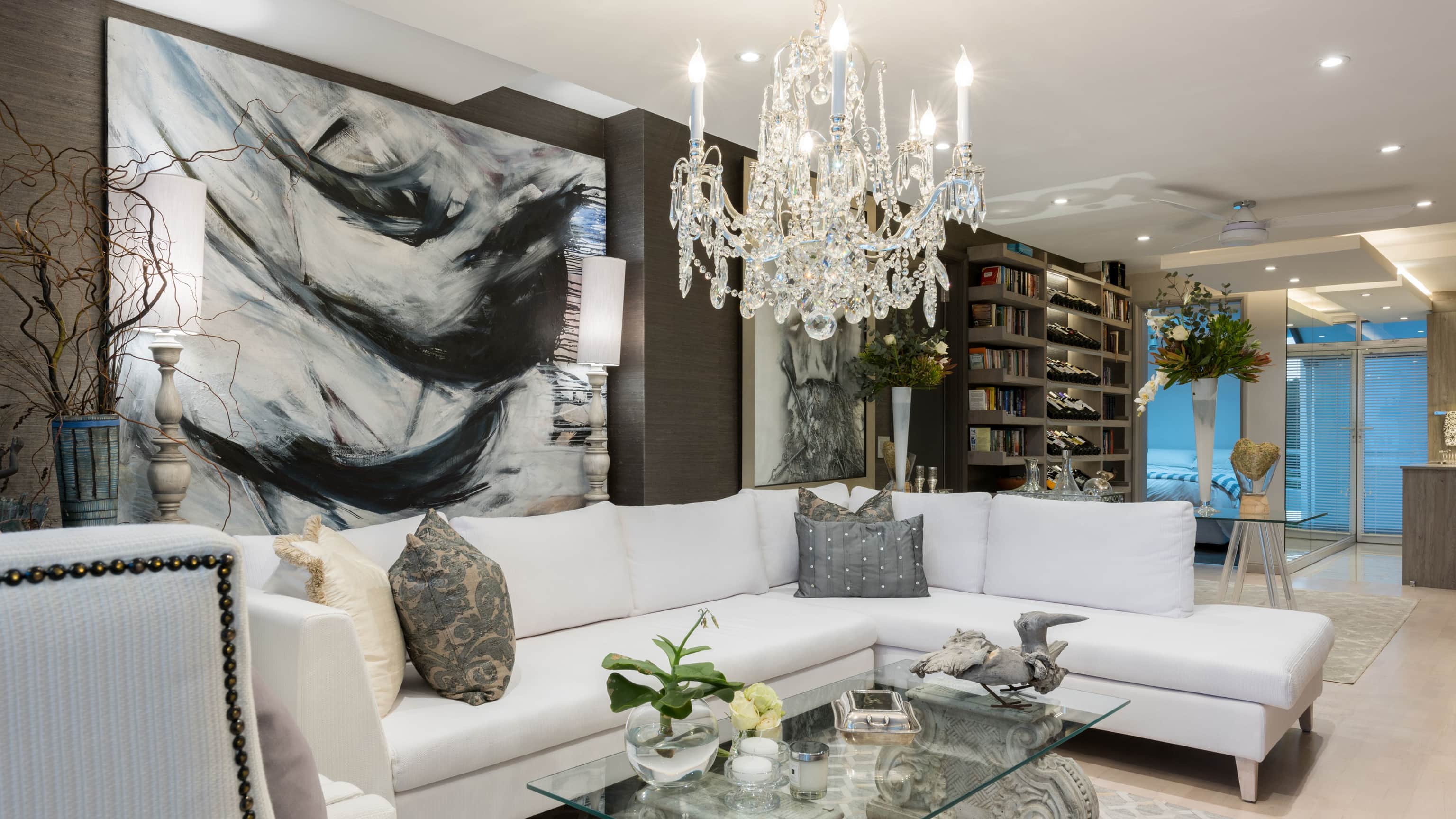 Lounge with white sofas, a crystal chandelier, charcoal grasscloth walls and a large abstract canvas