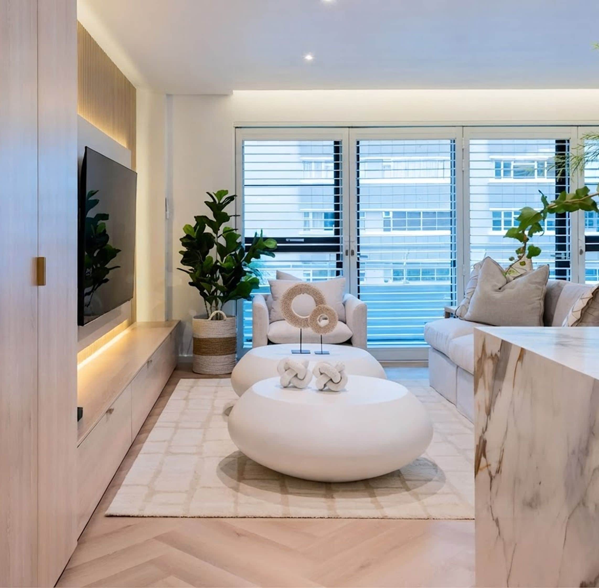 Living room with a herringbone floor, white oval coffee tables, a fiddle-leaf fig and a marble counter