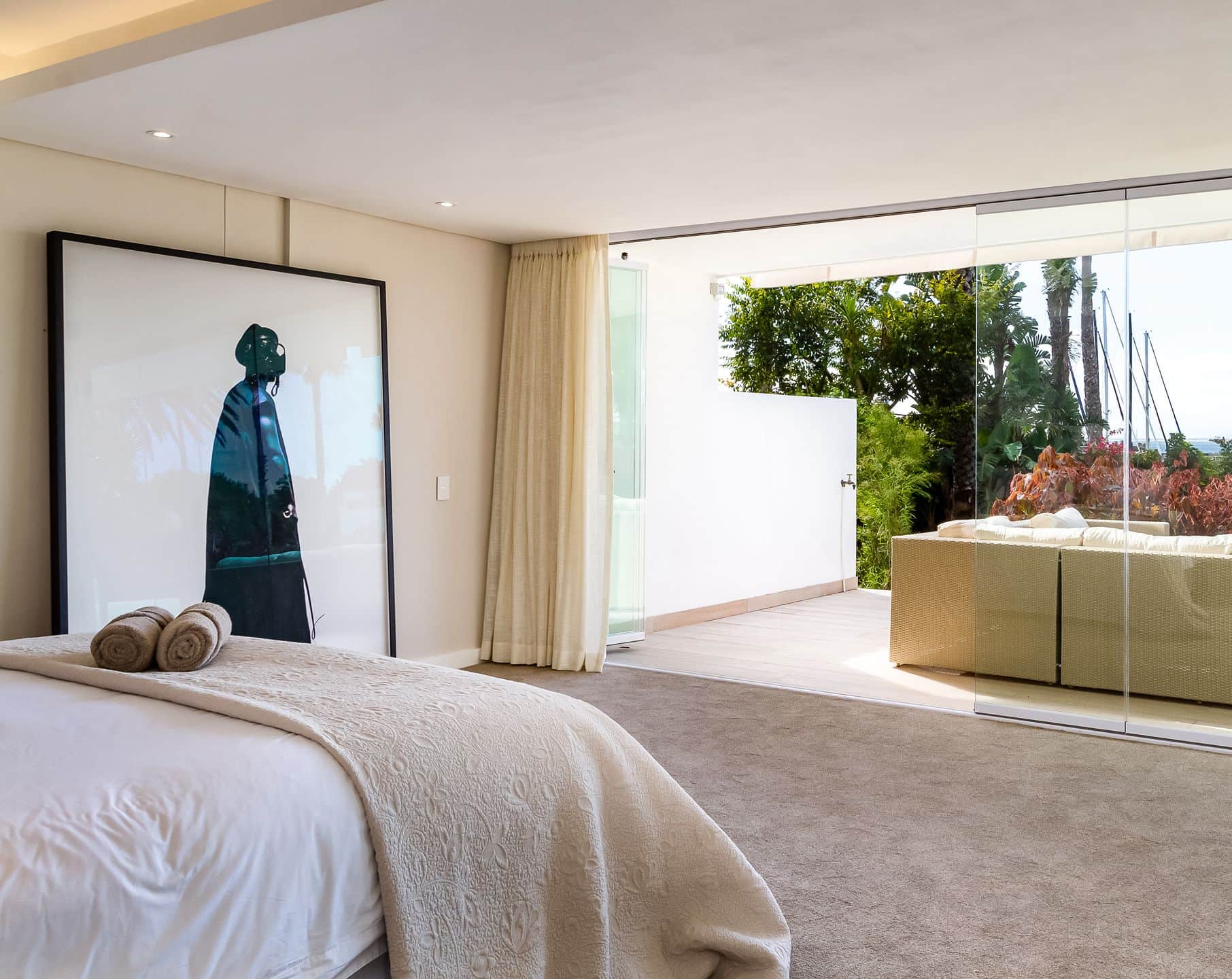 Bedroom with a large framed portrait and sliding glass doors opening to a garden terrace